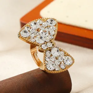 Elegante anello a fiocco dorato con strass di cristallo per donna su sfondo seta
