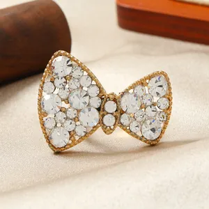 Dettaglio dell'anello a fiocco dorato con strass scintillanti su sfondo in tessuto