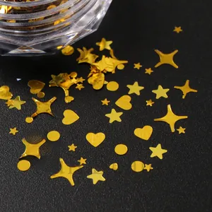 Close-up of golden stars and hearts nail art sequins scattered on a black background