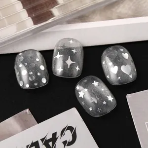 Macro view of silver star and heart nail art stickers on gray cat-eye gel nails