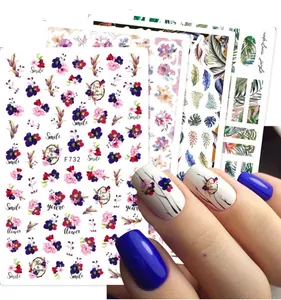 Dettaglio di adesivi nail art floreali con foglie e scritte in inglese sulla superficie dell'unghia