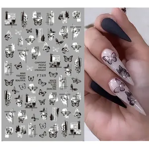 Detail of 3D black butterfly nail stickers with artistic lettering on stiletto nails