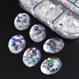Macro detail of oval resin nail charms with iridescent glitter and metallic star shapes