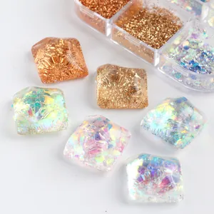 Makroaufnahme quadratischer Harz-Nagelsteine mit champagnergoldenem Glitter und Pailletten