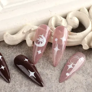 Dettaglio unghie a mandorla con motivi luna e stelle su base glitter rosa e marrone