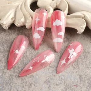 Dettaglio di unghie a stiletto rosa marmorizzato con adesivi bianchi a forma di nuvola