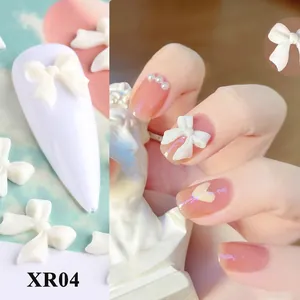 Dettaglio di fiocchi 3D bianchi opachi per nail art applicati su unghie e tips