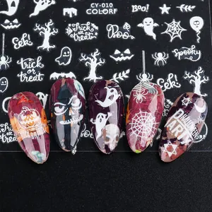 Detail of Halloween nail stickers with white ghosts and pumpkins on dark purple nails