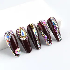 Detailed view of deep wine red coffin nails with AB crystal rhinestones and gold accents