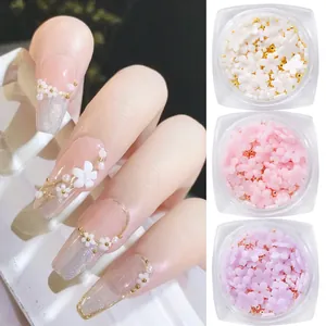 Detail of 3D nail art charms set with resin flowers, gold beads and pearls on nails