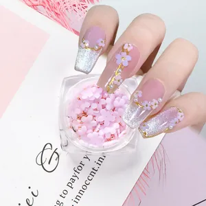 Macro shot of 3D pink resin flower nail charms with gold beads for floral manicure design