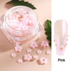 Detail of pink resin flowers and golden beads on purple nails with square bottle