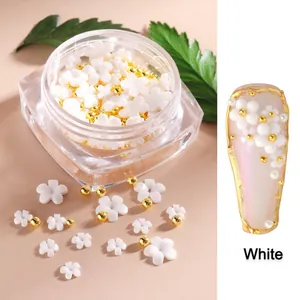 Detail of 3D white resin flowers and gold metal beads for nail art in a square box