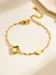 Detalle de la pulsera de acero de titanio dorado con dije de flor hueca e incrustación