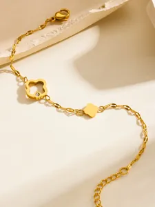 Primer plano de la pulsera de trébol en acero titanio dorado con colgante hueco y circon