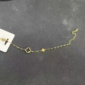 Pulsera de acero inoxidable dorada con dijes de trébol calados y cristales finos