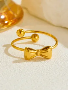 Detailed close-up of a rose gold open ring featuring a bow knot and spherical ends