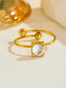 Detail of rose gold open ring with round cubic zirconia in a square setting and gold beads