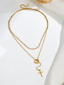 Detalle de collar dorado de doble capa con cuentas de satélite y colgante de cruz fina