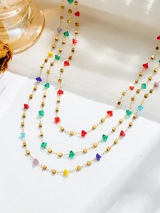 Detail van gouden ketting met kleurrijke kristallen kralen en gouden kubusvormige kralen