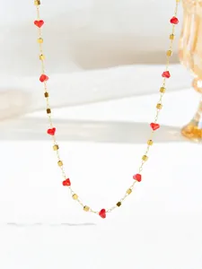 Detailopname van de gouden ketting met rode hartkristallen en goudkleurige metalen kralen