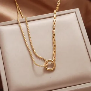Close-up of asymmetrical gold necklace with round bead and rectangular links in a velvet box
