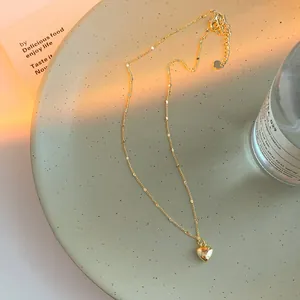 Golden heart pendant necklace on minimalist O-chain with lobster clasp and warm lighting