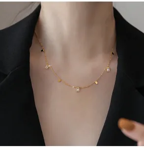Detailed close-up of a gold titanium necklace featuring square crystals on a black blazer