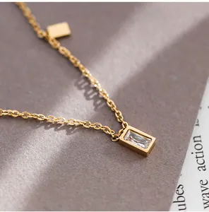 Detail of gold titanium necklace featuring a rectangular crystal pendant and minimalist charm