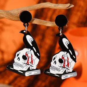 Gothic raven skull earrings on a dry branch with a moody orange background for Halloween