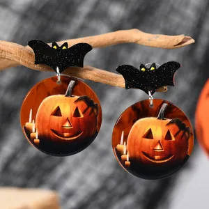 Detalle macro de pendientes de Halloween con diseños de murciélago y calabaza linterna