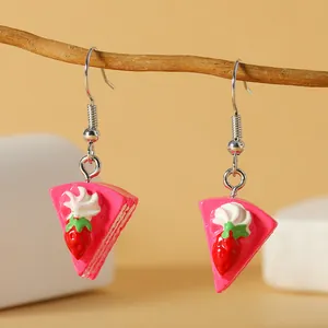 Detailopname van een handgemaakte aardbeientaart oorbel die aan een houten takje hangt