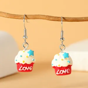 Detailopname van handgemaakte cupcake-oorbellen met Love-tekst en kleurrijke sterren