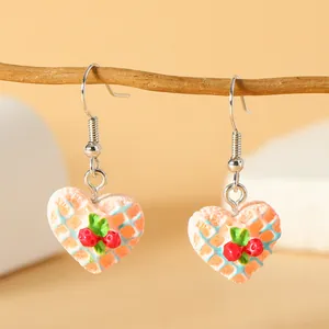 Creatieve hartvormige wafel oorbellen met blauwe details en bessen aan houten tak