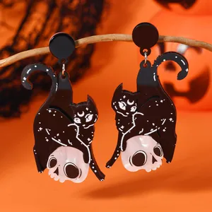 Gothic Halloween earrings featuring a black cat on a skull, hung on autumn branches