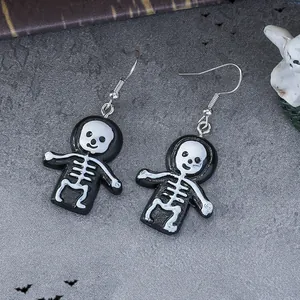 Close-up of gothic skull earrings with black hoodie design on dark textured background