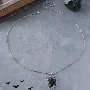 Detailed macro of gothic bat necklace featuring an oval black stone and silver chain