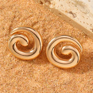 Minimalist irregular spiral gold alloy earrings on beach sand and rock background