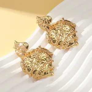 Detailed macro view of gold-tone irregular heart earrings with hammered metal texture