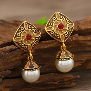 Nahaufnahme von Vintage-Glockenohrringen mit rotem Edelstein und weißen Perlendetails