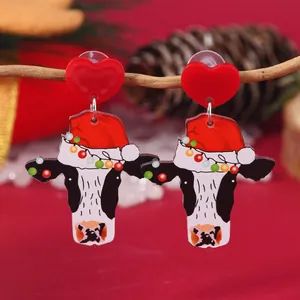 Close-up of festive acrylic cow earrings with Christmas hats hanging on branches