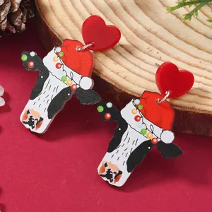 Detailed view of festive cow earrings with red Christmas hat on a rustic background