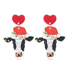 Close-up of festive acrylic drop earrings with cute cow wearing a Christmas hat