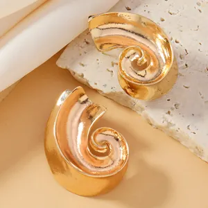 Dettaglio di orecchini a spirale dorati su pietra con sfondo di seta beige raffinato
