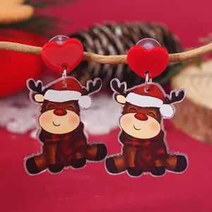 Detail of Christmas reindeer acrylic earrings with red heart studs hanging on a branch