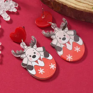Close-up of Christmas reindeer acrylic earrings with red heart studs on festive background
