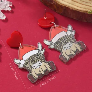 Close-up of highland cow Christmas earrings with size specs and festive decor