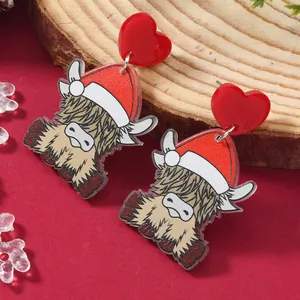 Detail of Christmas highland cow acrylic earrings with red heart studs on wood