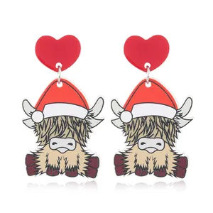 Detail of Christmas earrings featuring red heart studs and cute Highland cow charms
