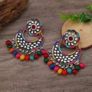 Detail of bohemian drop earrings with colorful resin beads and teardrop crystals on wood